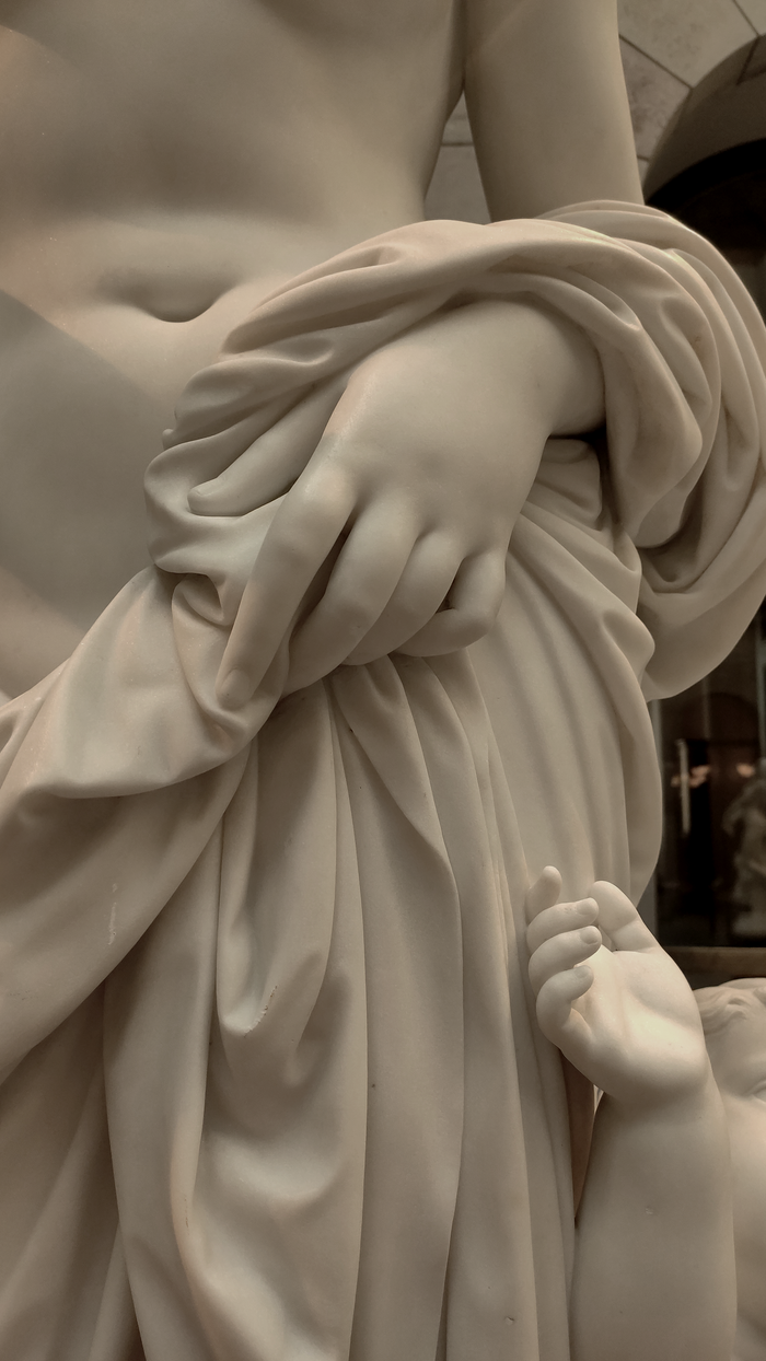 our-experience Detailed close-up of a marble statue depicting a mother and child's hands, showcasing classical artistry.